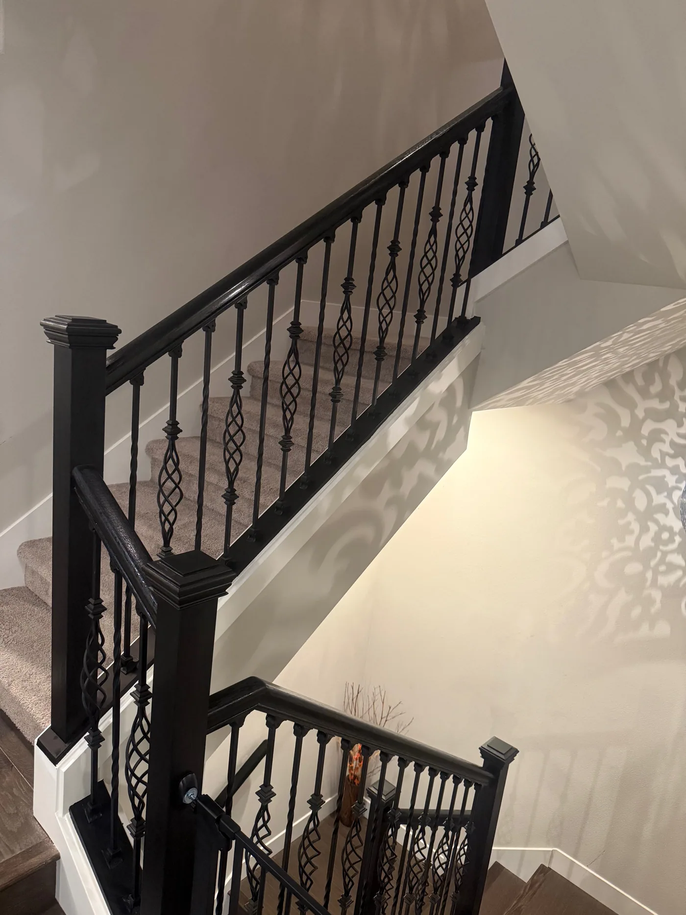 Dark wood handrail with decorative black metal balusters in a finished stair renovation